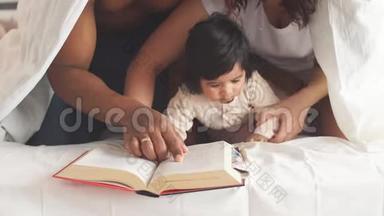 一个多种族的家庭在卧室的毯子下面读一本儿童`<strong>百科</strong>全书